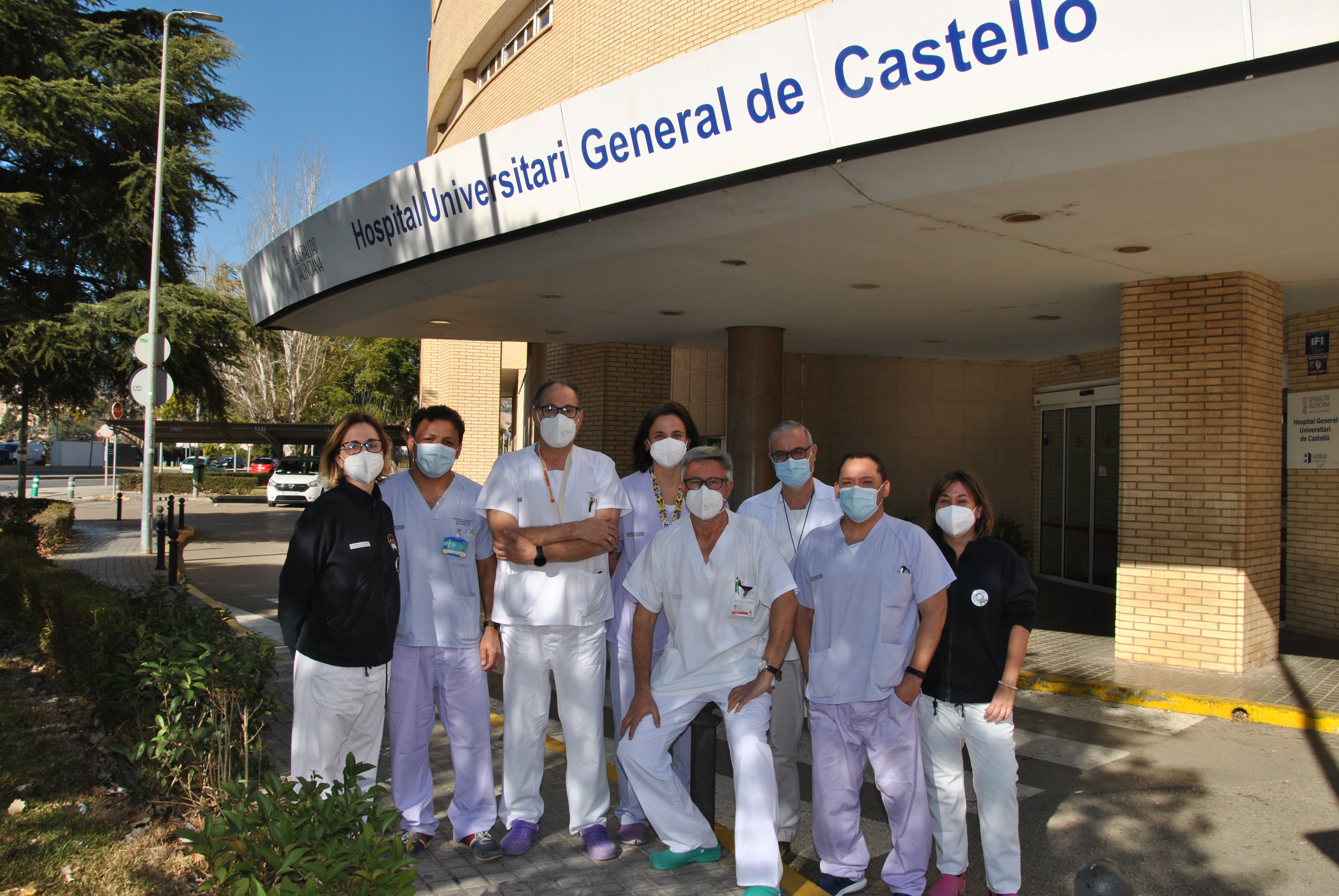 grupo de sanitarios hombres y mujeres posan frente a la puerta principal del hospital general universitario de castellón
